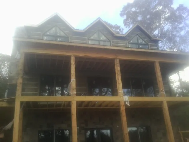 Dormers and porch framing on a large log home under construction — Roof Coating work by our crew in Willard