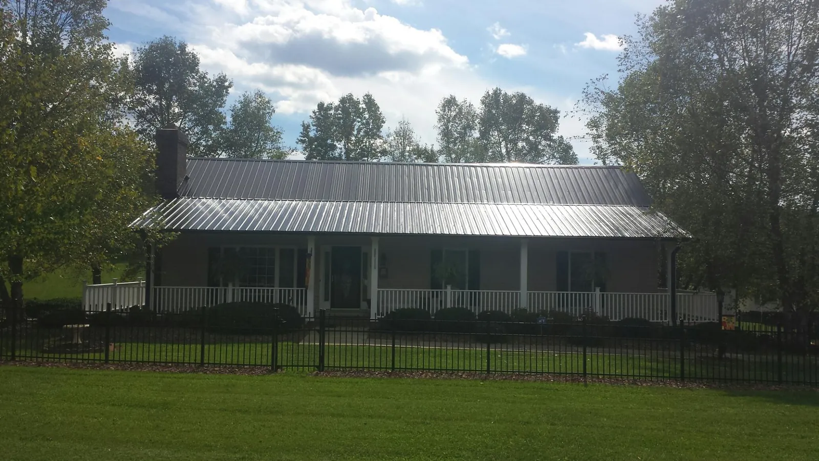 Gray metal roof on a brick ranch with a full width front porch — Gutter Guard Installation work by our crew in Willard